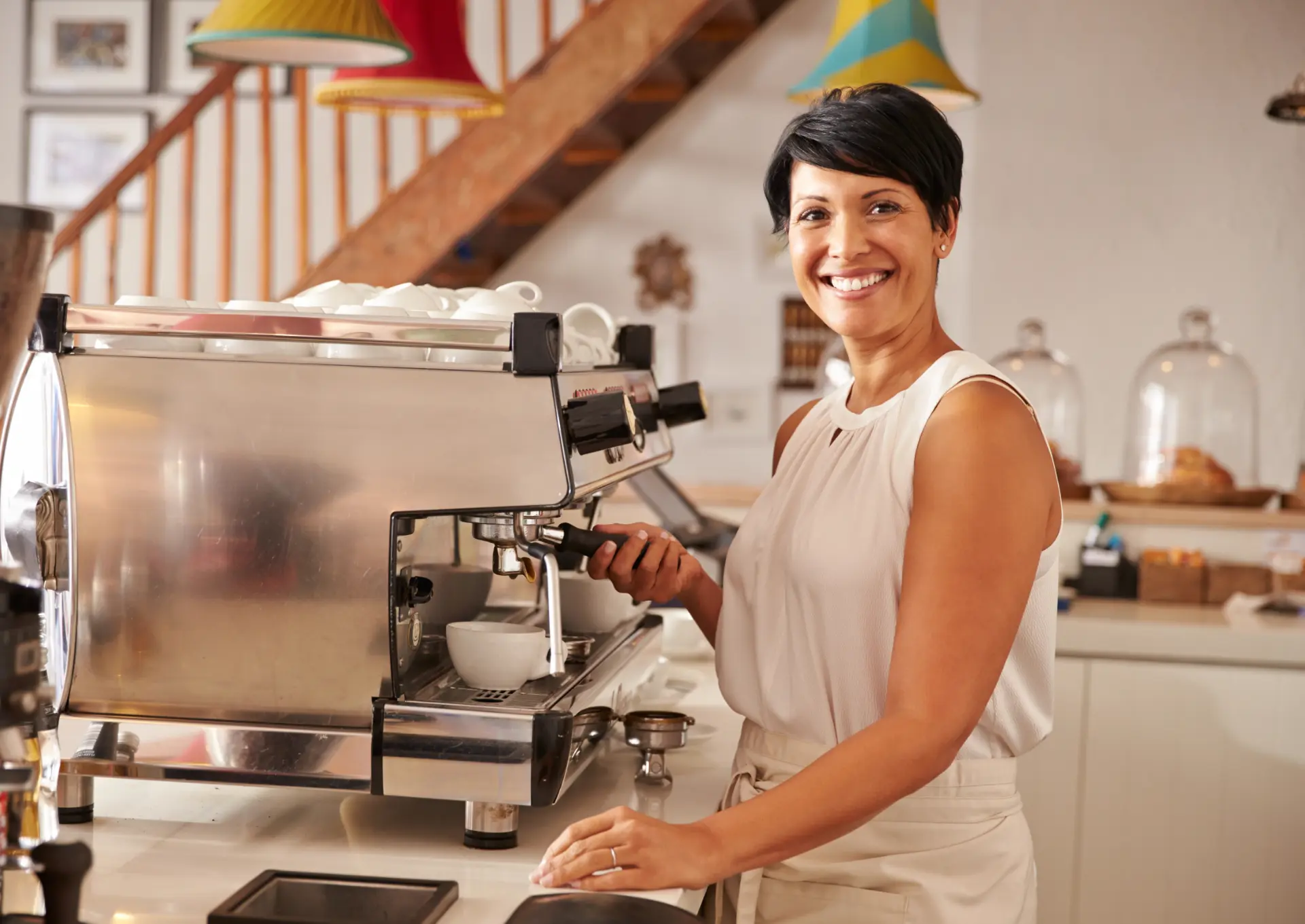 Small business owner smiling behind the espresso machine in her cafe