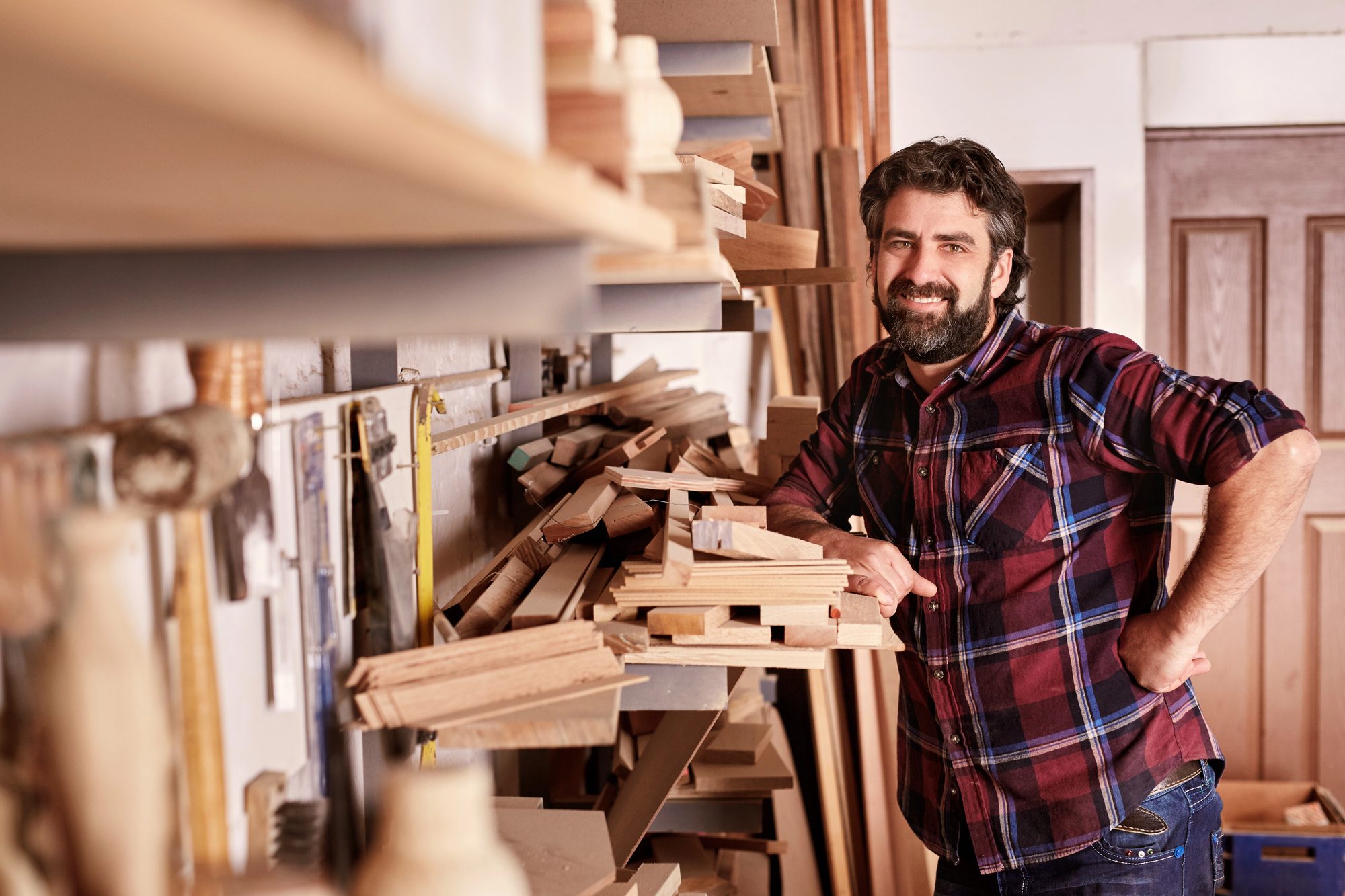 Workshop owner smiling in his shop, back at the craft he built the business around