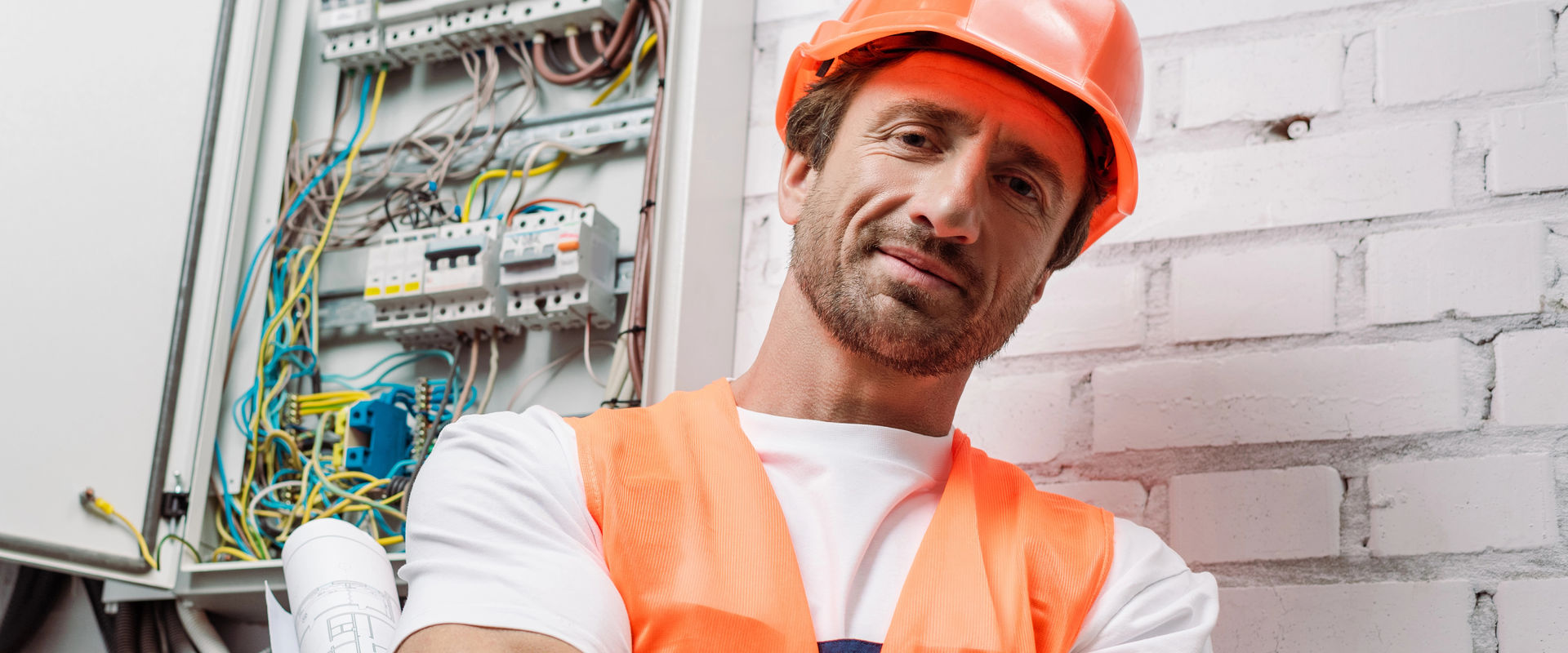 Panoramic shot of electrician with blueprint looking at camera
